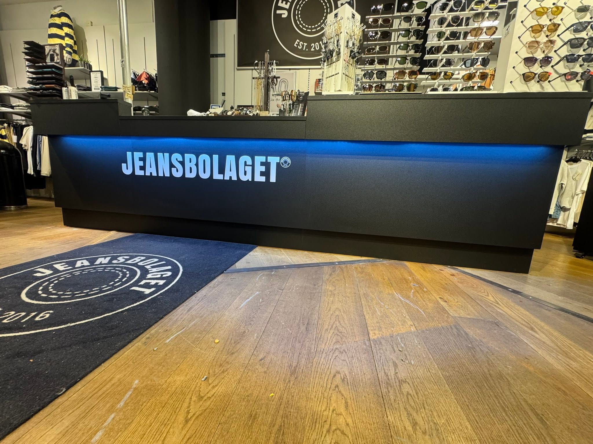 Butikskassa hos Jeansbolaget med klädställ och solglasögon bakom disken