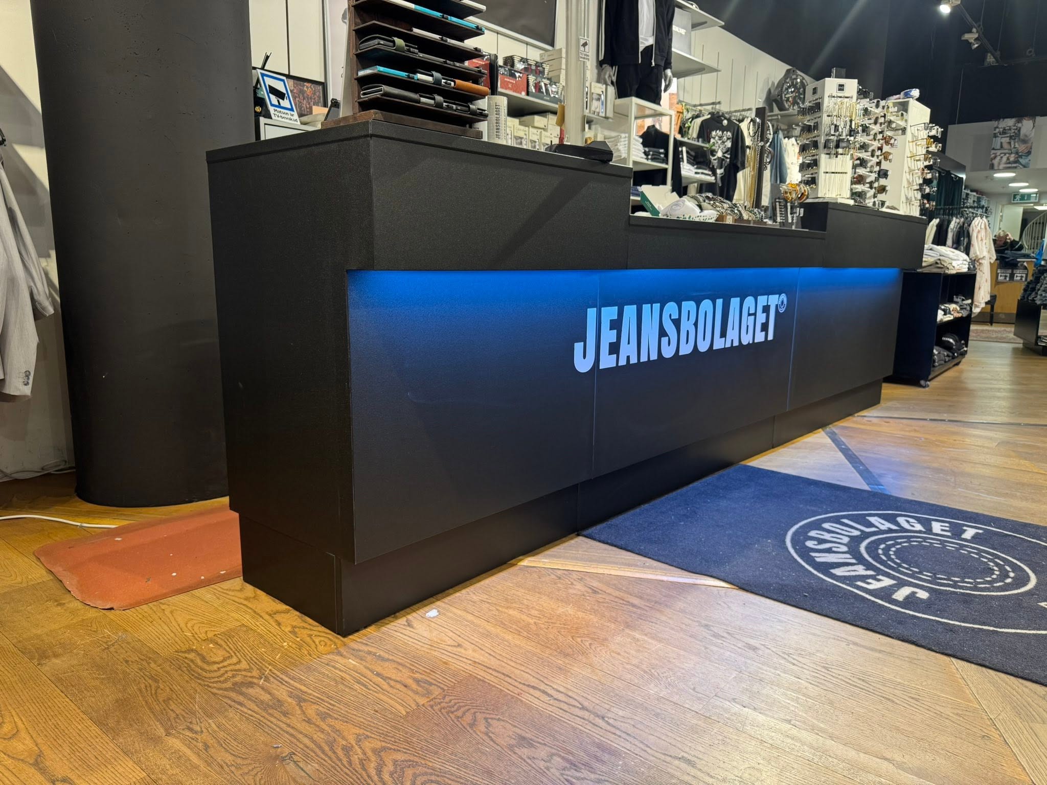 Front på Jeansbolagets kassa med belyst logotyp och logomatta