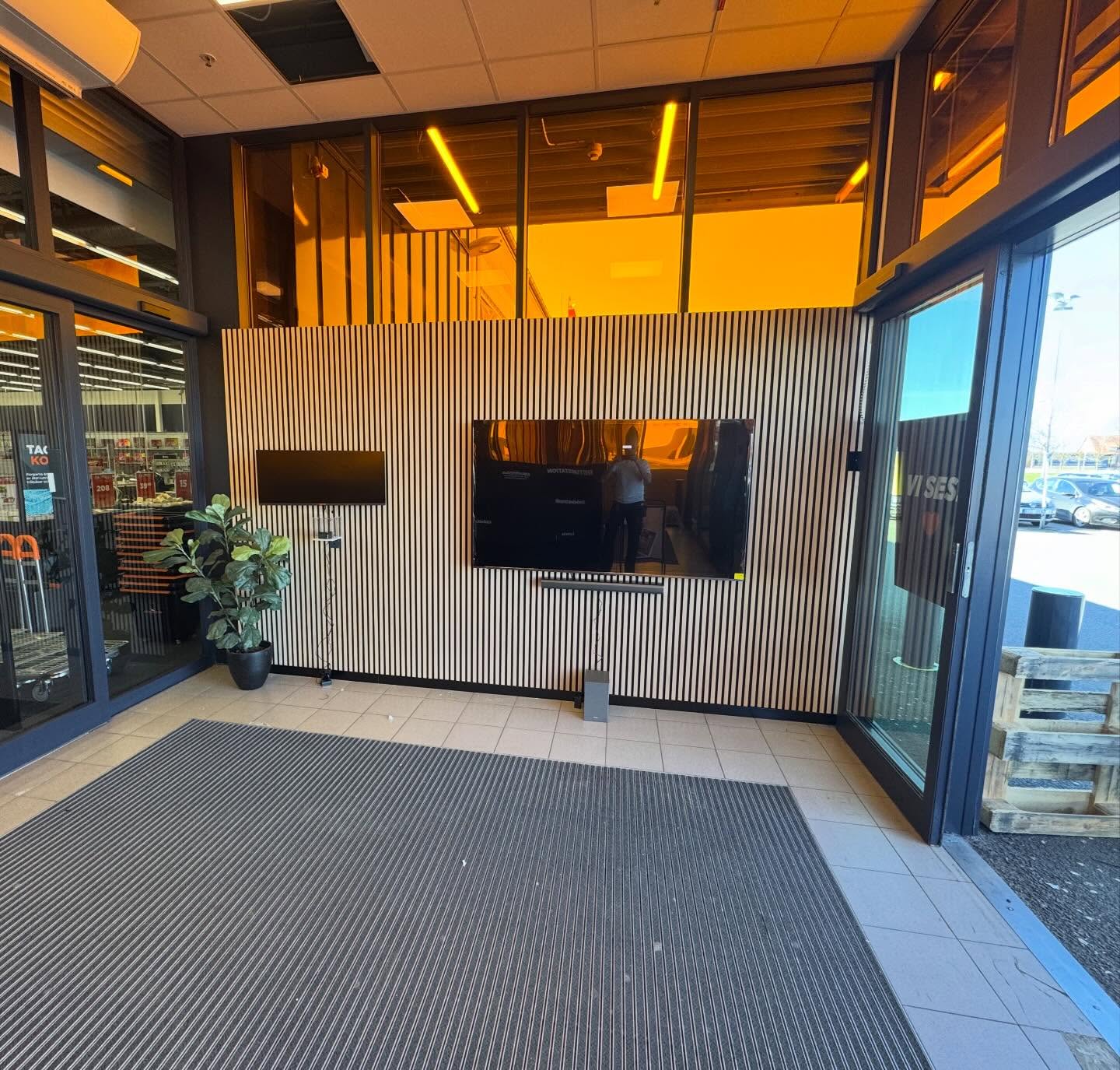 Entrévägg hos Power med träribbor, skärmar och glasdörrar