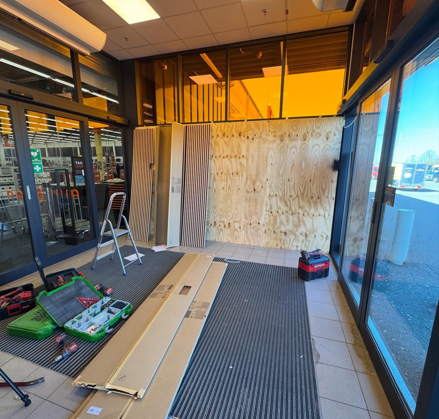 Montering av ribbvägg i butiksentré med verktyg och skivor på golvet