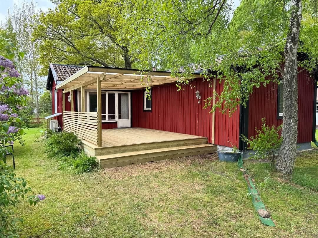 Altan med tak vid ett rött hus