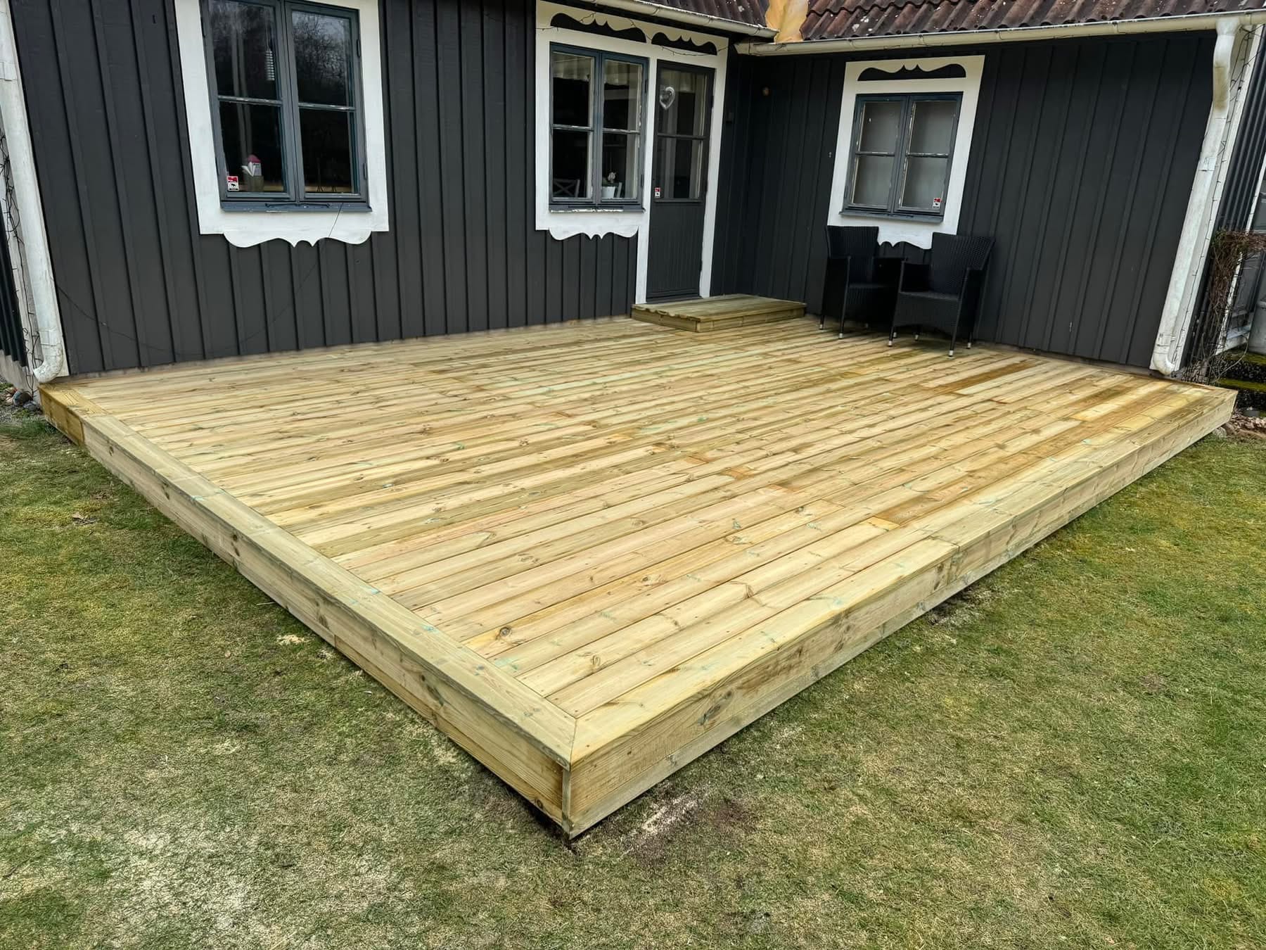 Trädäck vid ett svart hus