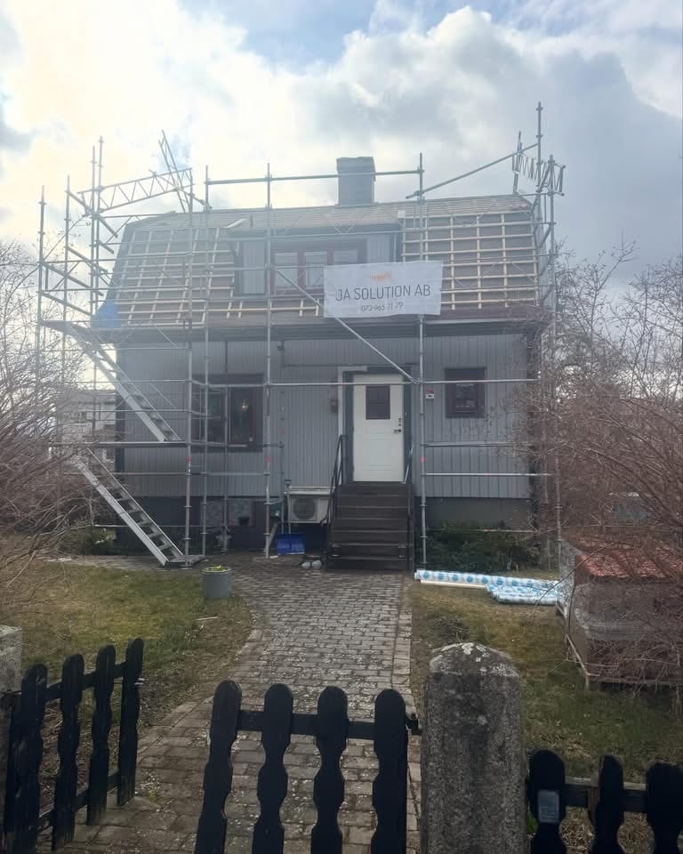 Hus under fasadrenovering med byggställning
