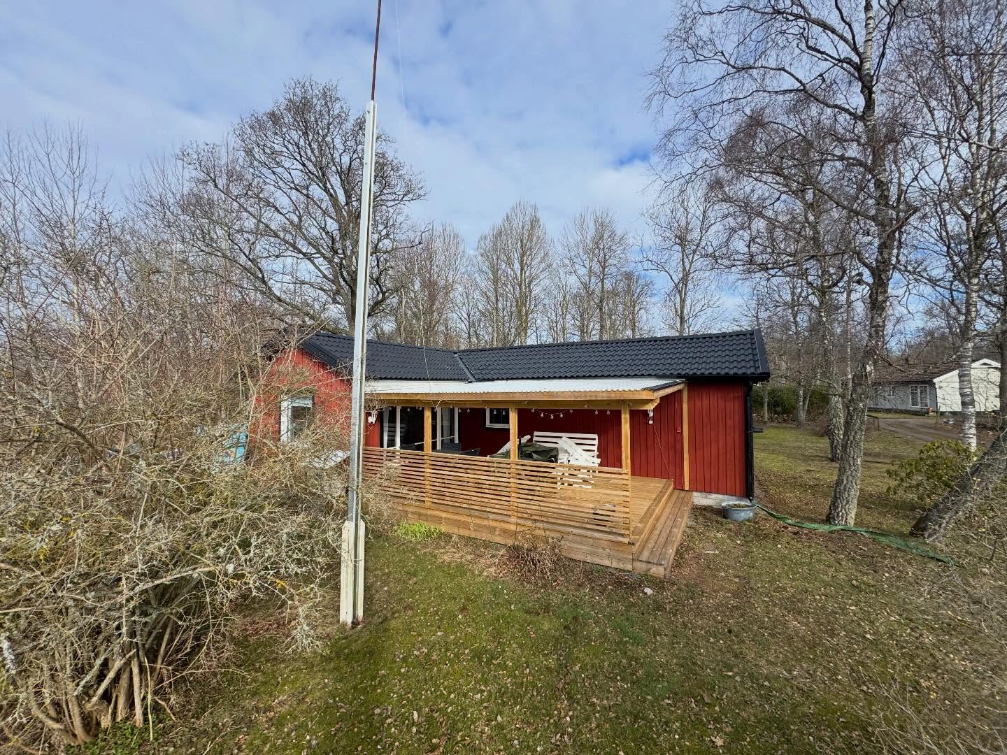 Röd villa med nytt svart tak, altan och räcke i ljust trä